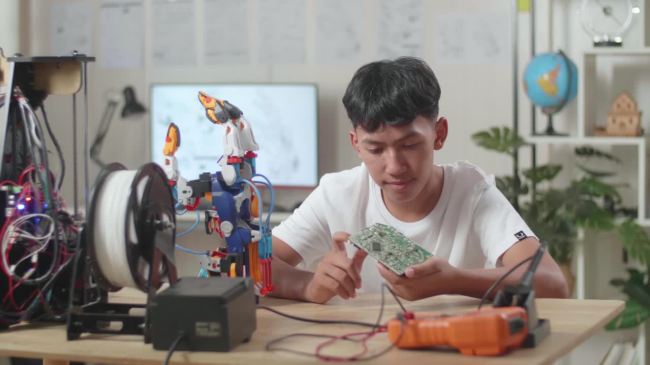 집에서 사이보그 손을 수리하는 동안 회로판을 들고 있는 아시아 소년