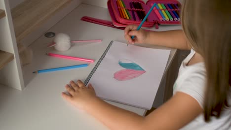 overhead of a little girl at her table drawing