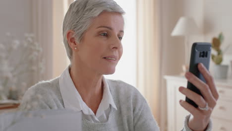 mujer madura feliz teniendo video chat usando un teléfono inteligente abuela disfrutando de la conversación con la familia compartiendo estilo de vida hablando por teléfono móvil con los nietos relajándose en casa 4k