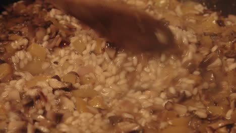 primer plano cinematográfico del chef mezclando risotto de hongos como burbujas de stock de verduras