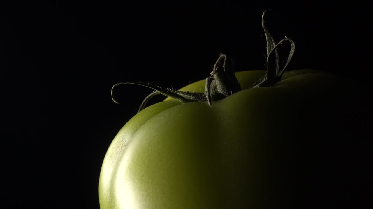 검은 바탕에 회전하는 초록색 토마토.