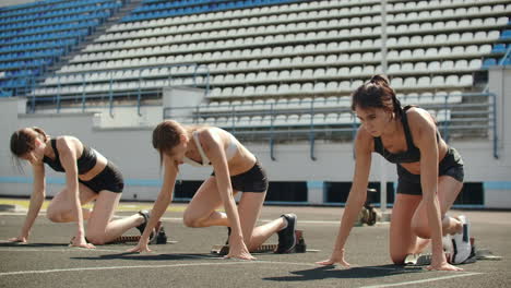 Female-runners-at-athletics-track-crouching-at-the-starting-blocks-before-a-race.-In-slow-motion.