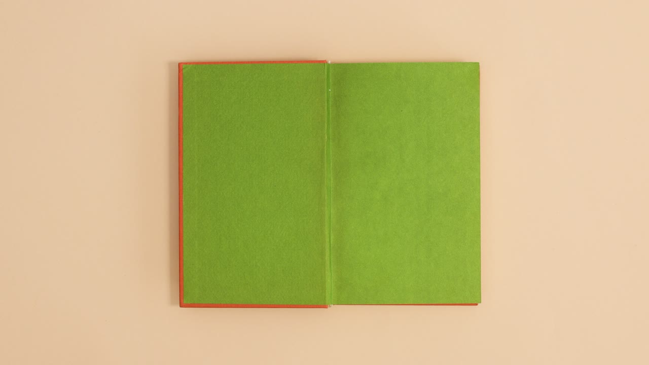 Orange hardcover vintage book appear and open with copy space on beige background. Stop motion flat lay
