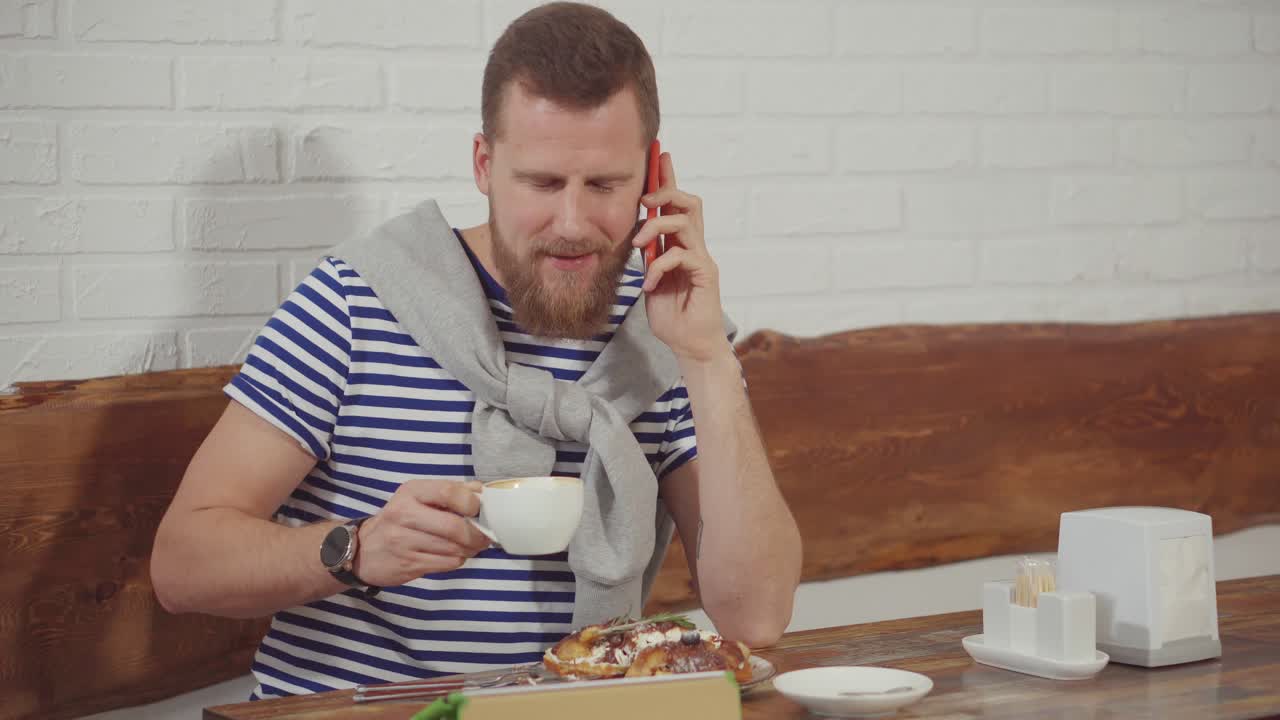hombre tomando el desayuno y hablando por teléfono en un café