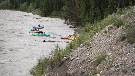 groups of people rafting down river in colorful rafts