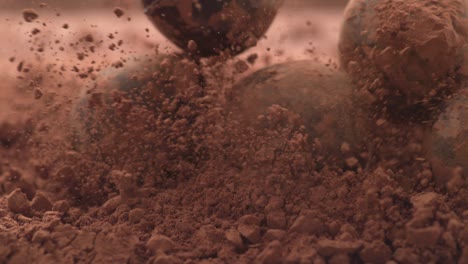 chocolate truffles falling into chocolate powder in super slow motion.