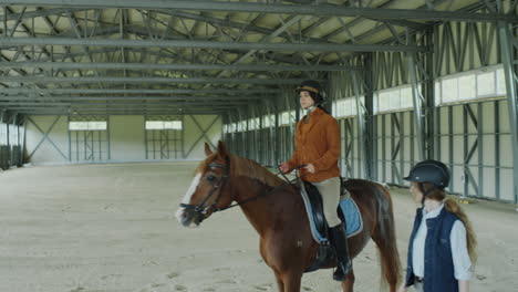 woman riding horse under control of instructor