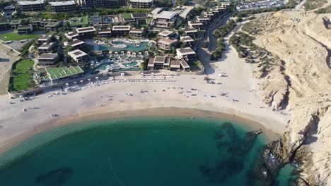 Aerial-dolly-shot-of-a-paradisiacal-beach-bay-with-fine-golden-sand,-blue-sea-and-hotel-facilities-for-tourists-at-santa-maria-beach-in-cabo-san-lucas-in-mexico-during-an-unforgettable-vacation-trip