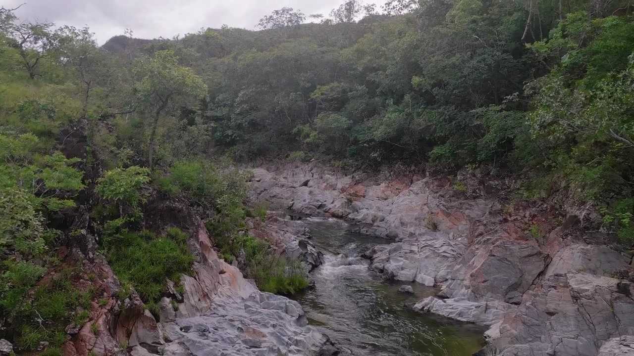 Fiume São Miguel che scorre attraverso un aspro canyon di quarzite nella Serra do Segredo, Chapada dos Veadeiros, Goiás, Brasile, circondato da vegetazione preservata del Cerrado e antiche formazioni geologiche, vista aerea.