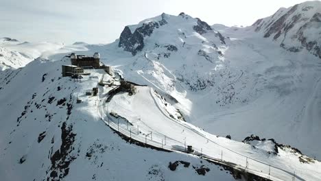 drone footage of the rocky ridge gornergrat, switzerland with a few skiers going down.