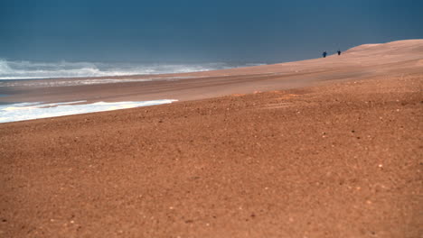 paisaje de playa con dos figuras humanas a lo lejos en praia do norte en nazare