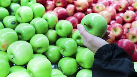 hand reaching for green apple in store