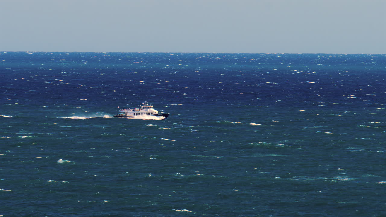 Nice, France - March 17, 2025: Distant view of a boat moving on the blue sea in daylight