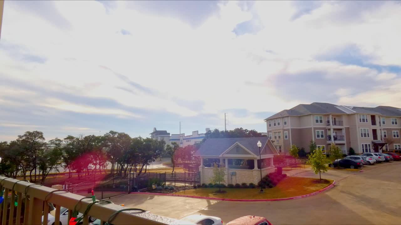 lapso de tiempo de las nubes que se mueven sobre la construcción con el destello de la lente del sol