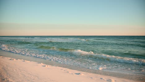 Aufnahmen-Des-Ozeans-An-Einem-Warmen,-Sonnigen-Abend-Mit-Fußspuren-Im-Sand