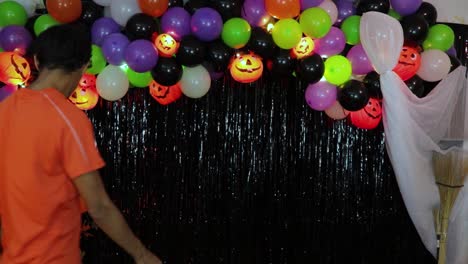 boy putting finishing touches on halloween decorations with pumpkins and balloons