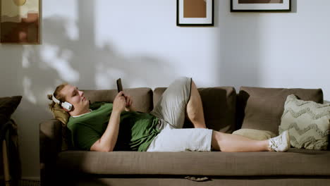 guy with headphones checking social media at home