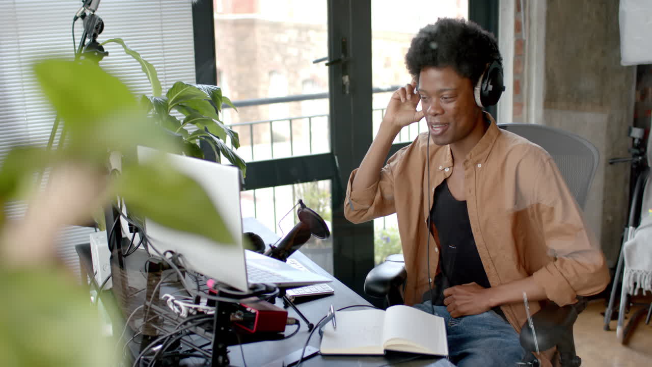 Happy african american man in headphones making live podcast from home, copy space, slow motion