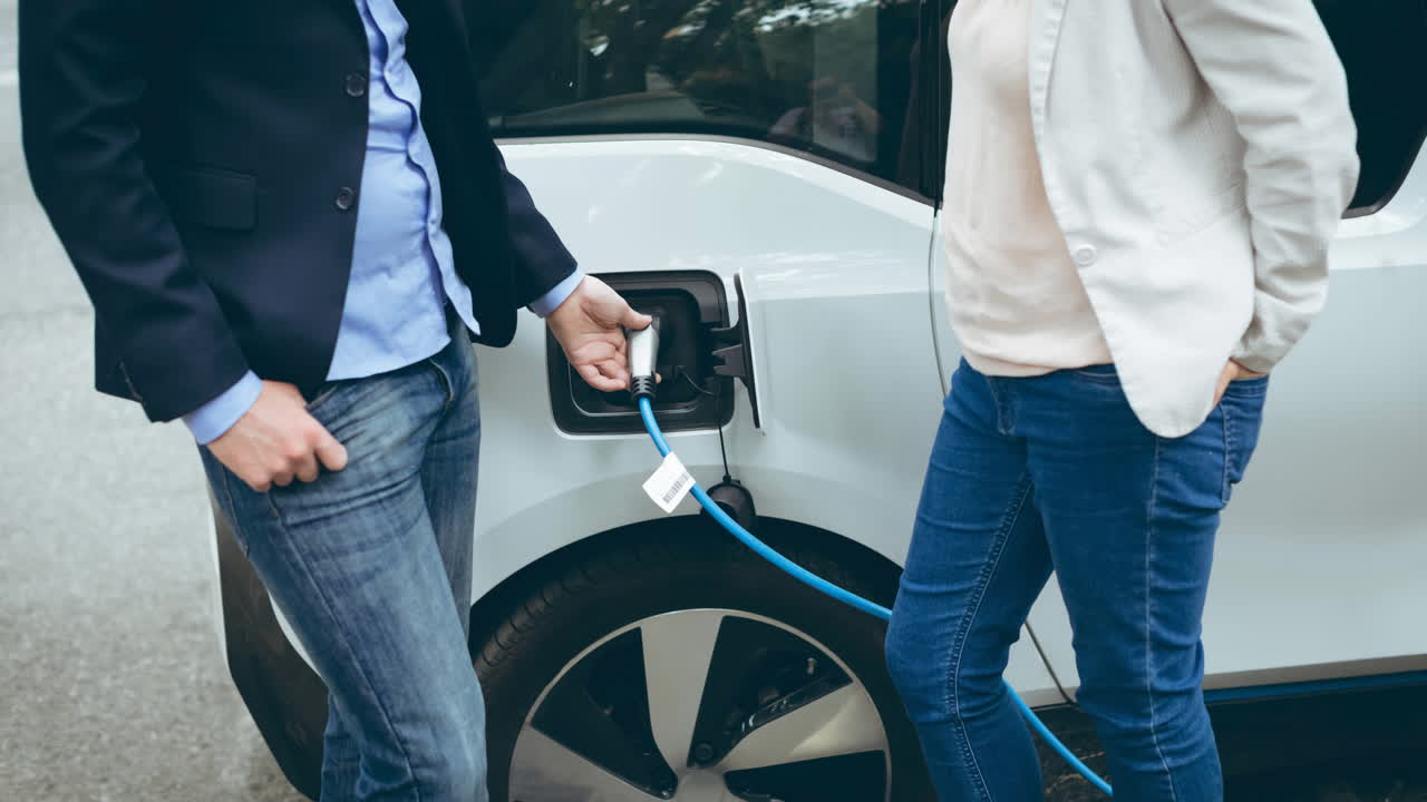 Elektrikli arabayı şarj eden beyaz erkek ve kadının orta bölümü.