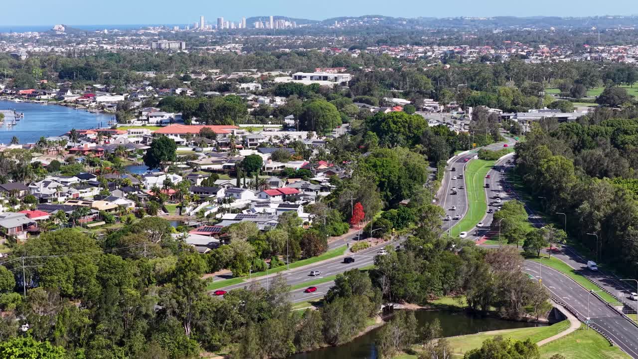 Daytime drone flyover of leafy suburban waterways, residential streets, and distant coastal skyline