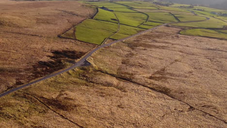 Drone-shot-of-the-West-Yorkshire-moorland-near-the-road-with-the-sunsetting-casting-golden-sun-on-the-hills