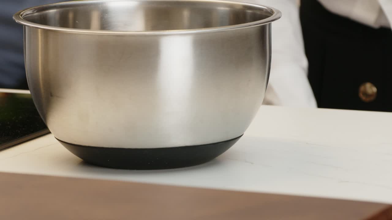 Close up of a stainless steel mixing bowl placed on a kitchen countertop