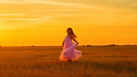 girl in pink dress twirling in a field at sunset