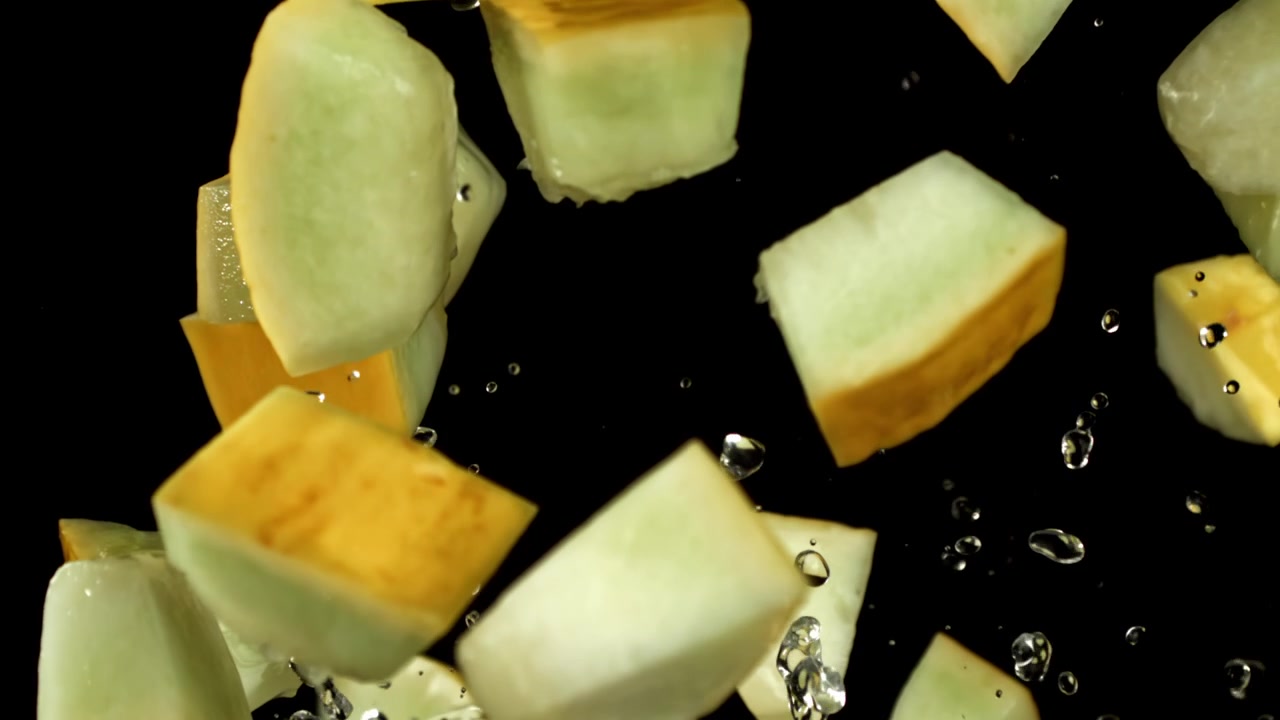 Fresh Diced Melon Cubes Falling with Water Splashes in Slow Motion