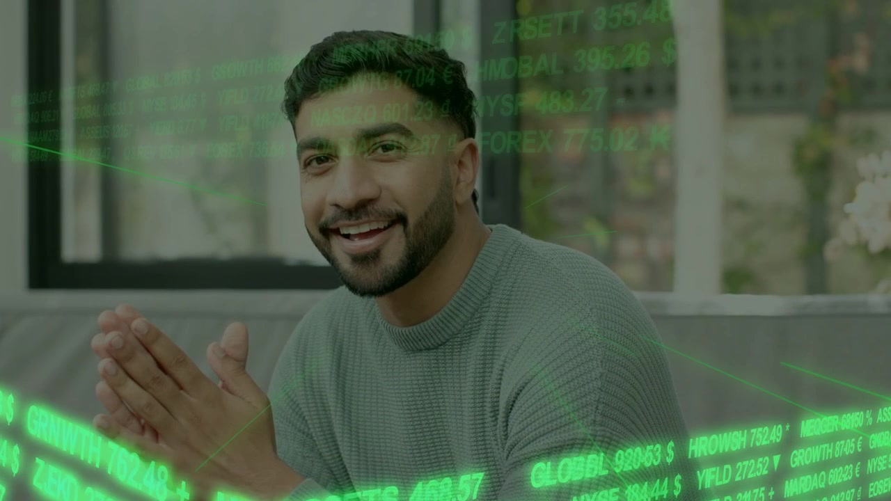 Man sitting gray sofa, clasping hands, opening eyes, smiling, reacting to sweeping financial ticker