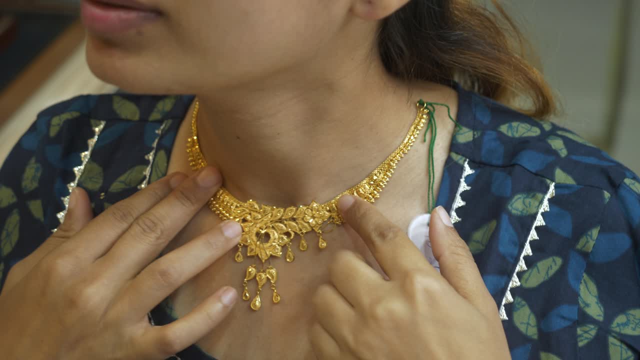 Young Indian asian woman wearing designer gold necklace at gold shop, 18k HUID certified gold necklace, Closeup