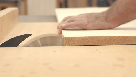 craftsman cuts wood boards with table saw in slow motion close up