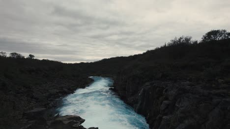 Aerial-clear-blue-waterfall-river-hlauptungufoss-Iceland,-flying-over-foaming-waves