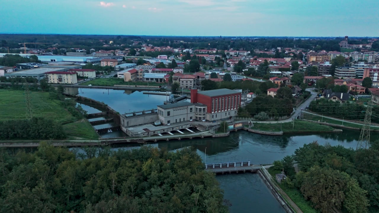 Veduta aerea di una centrale idroelettrica su un fiume, che genera energia rinnovabile dal flusso dell'acqua con una diga e turbine al crepuscolo