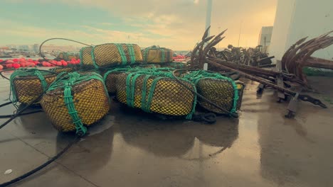 fishing equipment lies atop the damp asphalt in a spanish coastal town, featuring metal anchors and nets, symbolizing the essence of maritime livelihood and coastal tradition