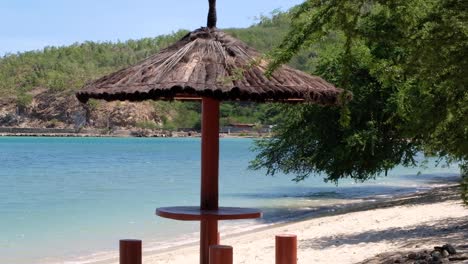 vista de la pintoresca zona de picnic con techo de paja parasol en la playa de arena blanca en dili, timor-leste, sudeste asiático