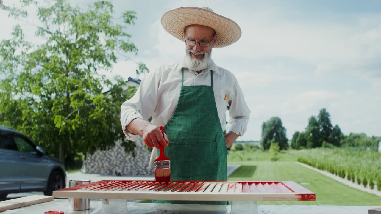 hombre mayor pintando persianas de madera al aire libre