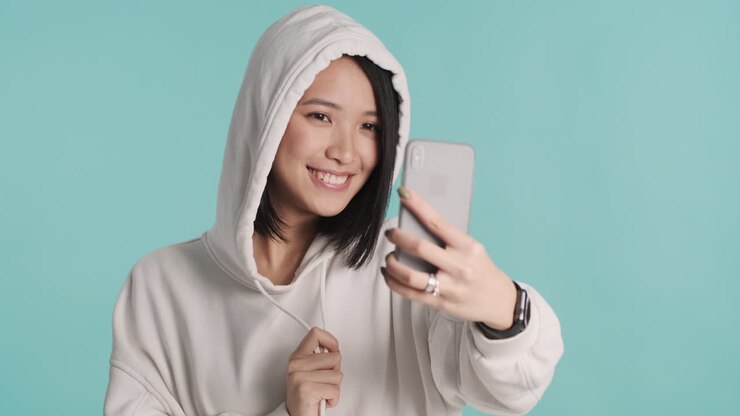 Asian woman taking selfie on smartphone.