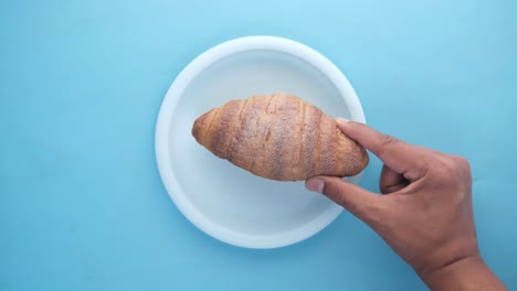 mano con un croissant en un plato