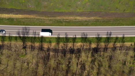 aerial shot of traffic on highway through wooded landscape, drone pov