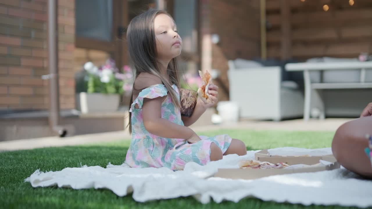 una madre e hija disfrutan de un picnic de verano al aire libre en un césped cubierto de hierba, compartiendo pizza y pasando tiempo de calidad juntos en un día soleado. la escena de unión familiar refleja ocio y relajación.
