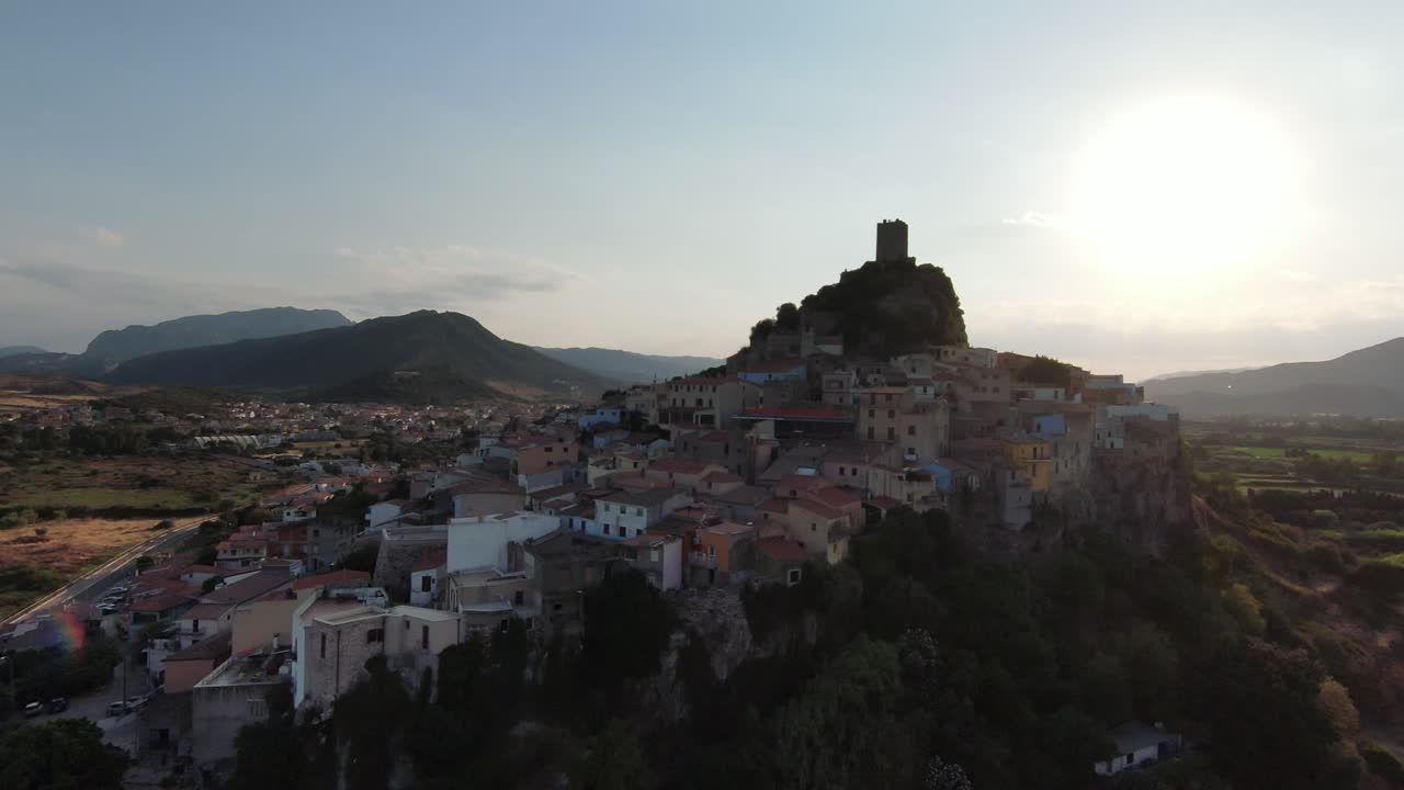 Panoramica a destra di un borgo antico su una collina, con una torre storica in cima.