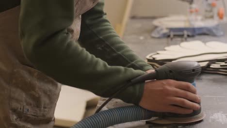 a carpenter grinds a piece of wood, plywood product made on a cnc laser machine with a grinder