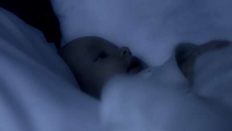 close-up of white wad of a baby awake in the night in his parents' bed