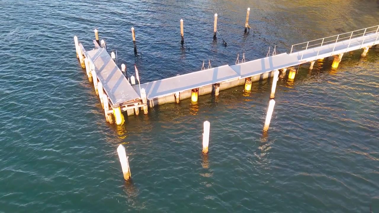 High angle drone shot of a wooden pier over calm blue water in Nelson Bay.