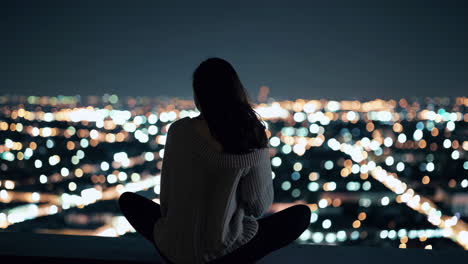 woman contemplating city lights at night