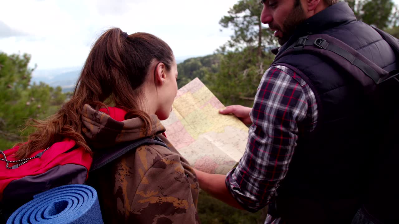 Hikers couple standing on top of mountain with a map