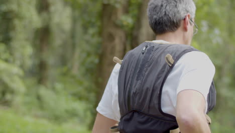 Man-in-eyeglasses-running-on-trail-in-forest