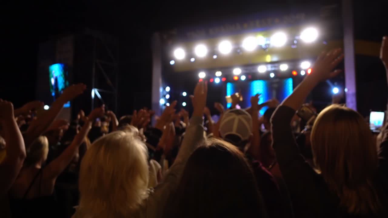Concerto sul palco. Folla di persone e musicisti sulla scena. Fuori fuoco