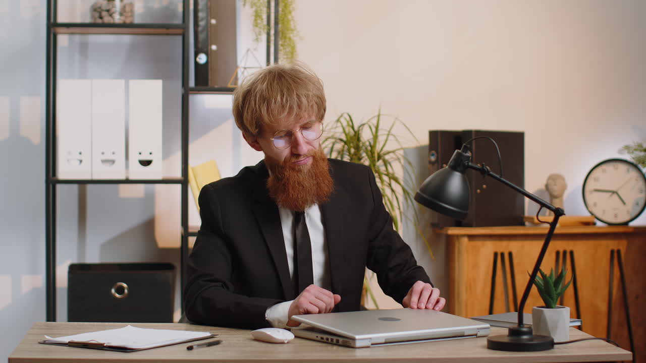 Businessman working on laptop meditating doing yoga breathing exercise in lotus position at office