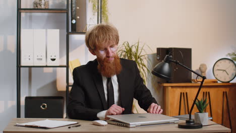 businessman working on laptop meditating doing yoga breathing exercise in lotus position at office